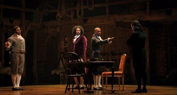 Movie still from “Hamilton” (2020), directed by Thomas Kail – Two men are standing in front of a table; Wide shot, Over the shoulder angle