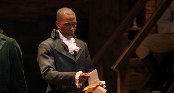 Movie still from “Hamilton” (2020), directed by Thomas Kail – A man in a black jacket and white shirt holding papers; Medium shot, Over the shoulder angle