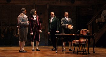Movie still from “Hamilton” (2020), directed by Thomas Kail – A group of men standing on top of a wooden floor; Wide shot, High angle