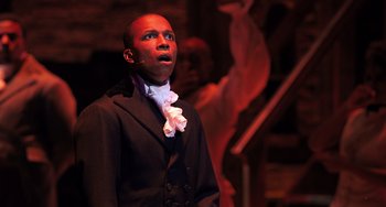 Movie still from “Hamilton” (2020), directed by Thomas Kail – A man wearing a black suit and a white bow tie; Close Up shot, High angle