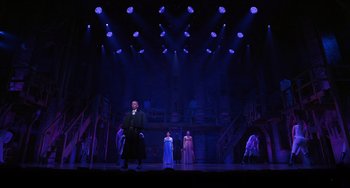 Movie still from “Hamilton” (2020), directed by Thomas Kail – A group of people standing on a stage in front of lights; Extreme Wide shot, Low angle