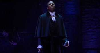 Movie still from “Hamilton” (2020), directed by Thomas Kail – A man wearing a black cape and a black and white outfit; Medium shot, Low angle
