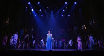 Movie still from “Hamilton” (2020), directed by Thomas Kail – A woman standing on a stage in front of a group of people; Extreme Wide shot, Low angle