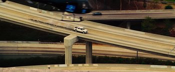Movie still from “Hancock” (2008), directed by Peter Berg – An suv is driving down a bridge over a freeway; Extreme Wide shot, High angle
