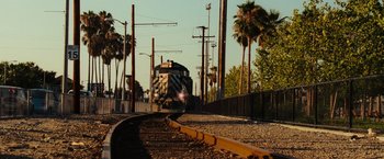 Movie still from “Hancock” (2008), directed by Peter Berg – A train traveling down train tracks next to palm trees; Extreme Wide shot, Low angle