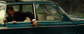 Movie still from “Hancock” (2008), directed by Peter Berg – A man leaning out of the window of a green car; Medium shot, Over the shoulder angle