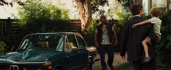 Movie still from “Hancock” (2008), directed by Peter Berg – A man standing in front of a parked car on the side of the road; Wide shot, Low angle