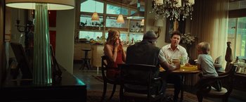 Movie still from “Hancock” (2008), directed by Peter Berg – A group of people sitting at a table in front of a window; Wide shot, Over the shoulder angle