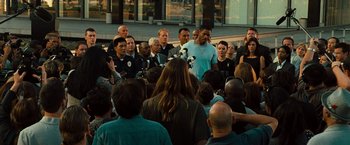 Movie still from “Hancock” (2008), directed by Peter Berg – A group of people standing around a crowd of people; Extreme Wide shot, Over the shoulder angle