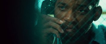 Movie still from “Hancock” (2008), directed by Peter Berg – A man talking on a phone behind a wire fence; Extreme Close Up shot, Overhead angle
