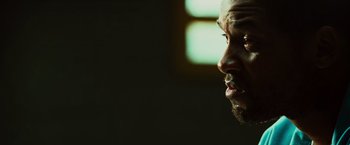 Movie still from “Hancock” (2008), directed by Peter Berg – A man's face in a dark room; Close Up shot, Over the shoulder angle