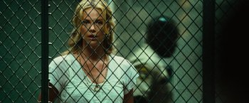 Movie still from “Hancock” (2008), directed by Peter Berg – A woman standing in front of a chain link fence; Close Up shot, Over the shoulder angle