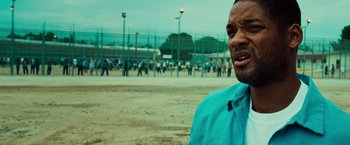 Movie still from “Hancock” (2008), directed by Peter Berg – A man standing in front of a crowd of people in a field; Close Up shot, Over the shoulder angle