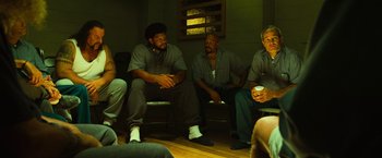 Movie still from “Hancock” (2008), directed by Peter Berg – A group of men sitting on top of a wooden floor; Wide shot, Over the shoulder angle
