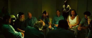 Movie still from “Hancock” (2008), directed by Peter Berg – A group of men sitting on a couch in a room; Medium shot, High angle
