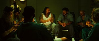 Movie still from “Hancock” (2008), directed by Peter Berg – A group of men sitting in a circle talking to each other; Medium shot, Over the shoulder angle