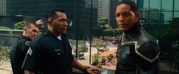 Movie still from “Hancock” (2008), directed by Peter Berg – Two police officers standing next to each other on a street; Medium shot, Over the shoulder angle