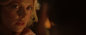 Movie still from “Hancock” (2008), directed by Peter Berg – A woman's face in a dimly - lit room; Close Up shot, Over the shoulder angle