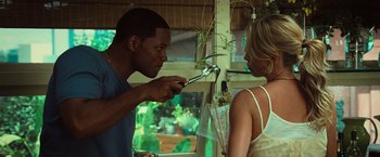 Movie still from “Hancock” (2008), directed by Peter Berg – A man and a woman in a room with plants in the background; Medium shot, Over the shoulder angle