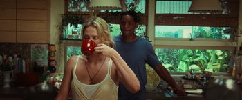 Movie still from “Hancock” (2008), directed by Peter Berg – A woman drinking a cup of coffee while standing next to a man; Medium shot, Over the shoulder angle