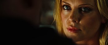 Movie still from “Hancock” (2008), directed by Peter Berg – A woman's face in a dimly - lit room; Close Up shot, Over the shoulder angle