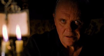 Movie still from “Hannibal” (2001), directed by Ridley Scott – An older man with a goatee is looking at the camera; Close Up shot, Over the shoulder angle