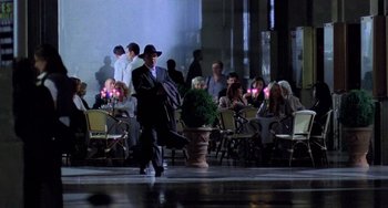 Movie still from “Hannibal” (2001), directed by Ridley Scott – A group of people sitting at tables with candles in the background; Wide shot, Over the shoulder angle