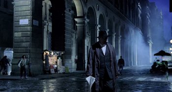 Movie still from “Hannibal” (2001), directed by Ridley Scott – A man walking down a street holding papers in his hand; Wide shot, Low angle