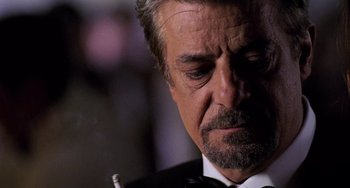 Movie still from “Hannibal” (2001), directed by Ridley Scott – An older man in a tuxedo looking down at a cigarette holder; Close Up shot, Over the shoulder angle