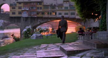Movie still from “Hannibal” (2001), directed by Ridley Scott – A man walking down a sidewalk near a bridge; Wide shot, Over the shoulder angle