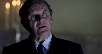 Movie still from “Hannibal” (2001), directed by Ridley Scott – An older man wearing a suit and tie looking up; Close Up shot, Low angle