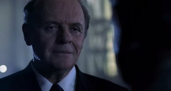 Movie still from “Hannibal” (2001), directed by Ridley Scott – An older man in a suit and tie smoking a cigarette; Close Up shot, Over the shoulder angle