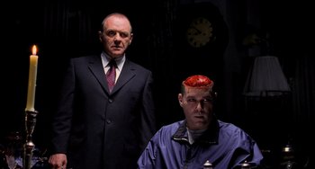 Movie still from “Hannibal” (2001), directed by Ridley Scott – Two men in suits and ties and a clock in the background; Medium shot, Over the shoulder angle