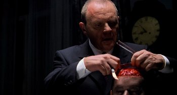 Movie still from “Hannibal” (2001), directed by Ridley Scott – A man in a black suit is cutting another man's hair; Close Up shot, Low angle