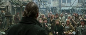 Movie still from “Hansel & Gretel: Witch Hunters” (2013), directed by Tommy Wirkola – A group of people gathered around a man in a crowd; Medium shot, Over the shoulder angle