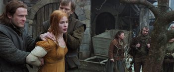 Movie still from “Hansel & Gretel: Witch Hunters” (2013), directed by Tommy Wirkola – A man and a woman standing next to each other in front of a stone wall; Medium shot, Low angle