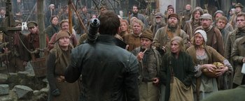 Movie still from “Hansel & Gretel: Witch Hunters” (2013), directed by Tommy Wirkola – A group of people standing around a man with a gun; Medium shot, Over the shoulder angle