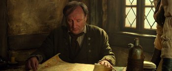 Movie still from “Hansel & Gretel: Witch Hunters” (2013), directed by Tommy Wirkola – A man sitting at a table looking down at papers; Close Up shot, High angle