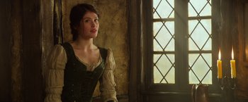 Movie still from “Hansel & Gretel: Witch Hunters” (2013), directed by Tommy Wirkola – A woman in a green dress standing in front of a window; Medium shot, Low angle