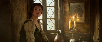 Movie still from “Hansel & Gretel: Witch Hunters” (2013), directed by Tommy Wirkola – A woman sitting in front of a window with a candle; Medium shot, Over the shoulder angle