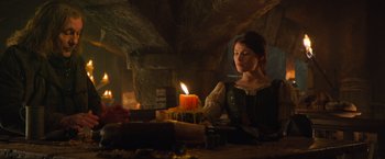 Movie still from “Hansel & Gretel: Witch Hunters” (2013), directed by Tommy Wirkola – A woman sitting in front of a cake with a lit candle; Medium shot, Over the shoulder angle