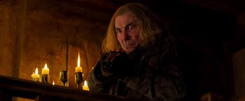 Movie still from “Hansel & Gretel: Witch Hunters” (2013), directed by Tommy Wirkola – A man with a long blonde hair is holding a gun in front of a lit candle; Medium shot, Low angle