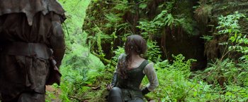 Movie still from “Hansel & Gretel: Witch Hunters” (2013), directed by Tommy Wirkola – A woman sitting on the side of a tree in the woods; Wide shot, Low angle