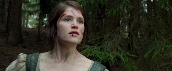 Movie still from “Hansel & Gretel: Witch Hunters” (2013), directed by Tommy Wirkola – A woman with a scar on her face is standing in the woods; Close Up shot, Low angle