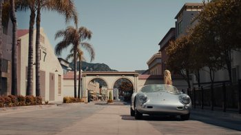 Movie still from “Happier Than Ever: A Love Letter to Los Angeles” (2021), directed by Patrick Osborne – A woman is sitting in the back seat of a silver car; Wide shot, High angle