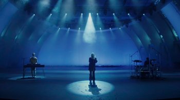 Movie still from “Happier Than Ever: A Love Letter to Los Angeles” (2021), directed by Patrick Osborne – A person standing on a stage in the middle of a room; Wide shot, High angle