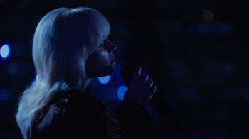 Movie still from “Happier Than Ever: A Love Letter to Los Angeles” (2021), directed by Patrick Osborne – A woman with blonde hair is holding a microphone; Close Up shot, High angle