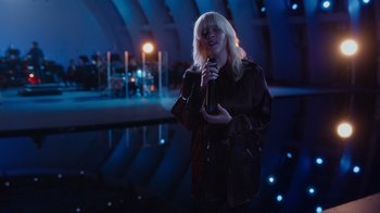 Movie still from “Happier Than Ever: A Love Letter to Los Angeles” (2021), directed by Patrick Osborne – A woman holding a microphone in front of an audience; Wide shot, High angle