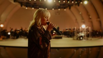 Movie still from “Happier Than Ever: A Love Letter to Los Angeles” (2021), directed by Patrick Osborne – A woman holding a microphone in her hand; Medium shot, Low angle