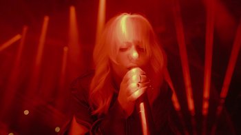 Movie still from “Happier Than Ever: A Love Letter to Los Angeles” (2021), directed by Patrick Osborne – A woman is singing into a microphone in the dark; Close Up shot, Low angle